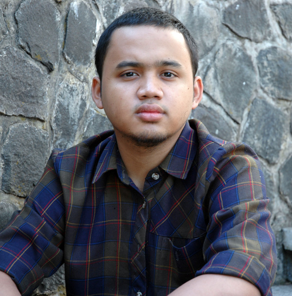 young person sitting against stone wall